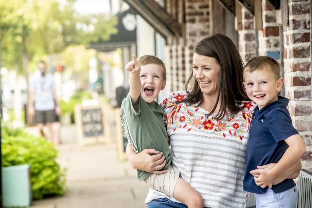 Young mother holding her two sons and smiling
