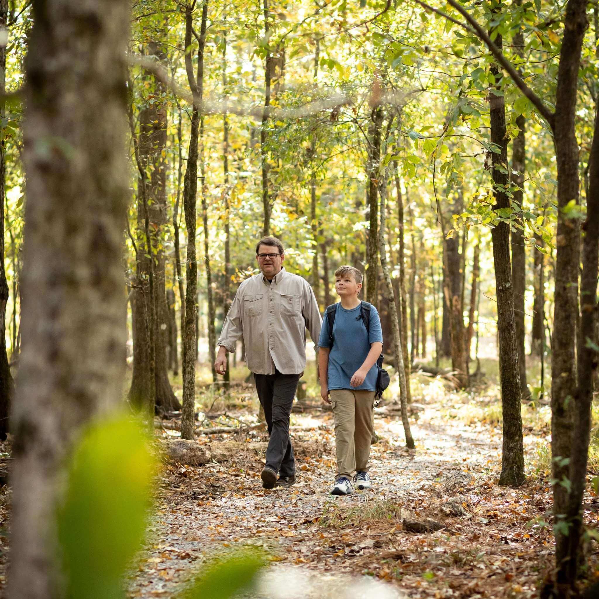 Man and boy hiking on a trail in a forest